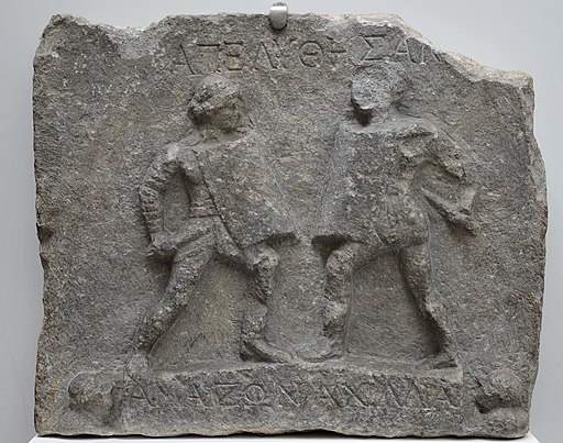 Marble relief with female gladiators, 1st-2nd century AD, from Halicarnassus (modern Bodrum, Turkey), British Museum (17590535705) by Carole Raddato is licensed under a Creative Commons Reconocimiento 4.0 Internacional License.Creado a partir de la obra en http://www.britishmuseum.org/explore/highlights/highlight_objects/gr/m/relief_female_gladiators.aspx.